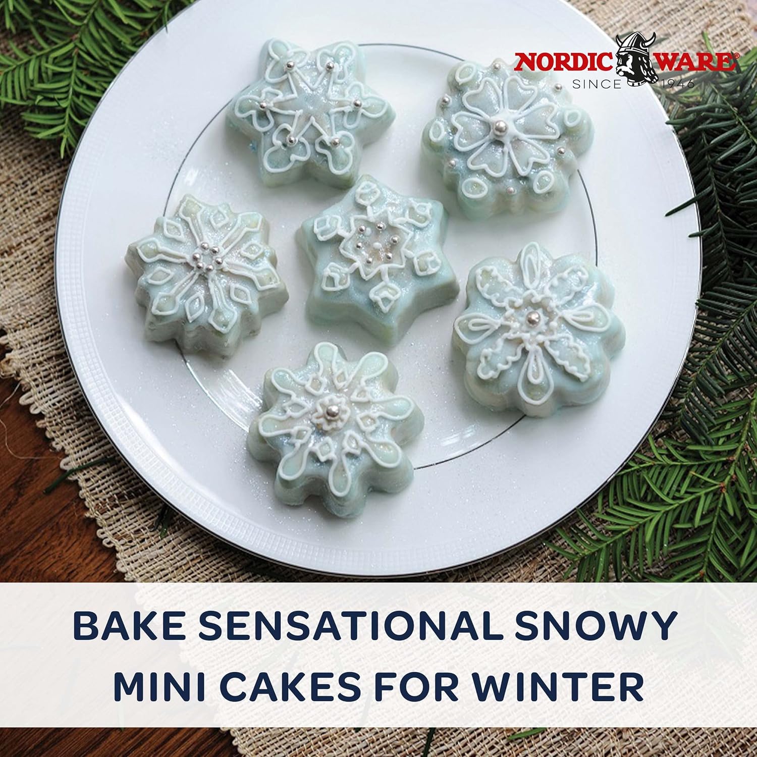 Mini frosted cakes on a plate with greenery and a table linen on a wooden surface with 'bake sensational snowy mini cakes for winter' text beneath it.