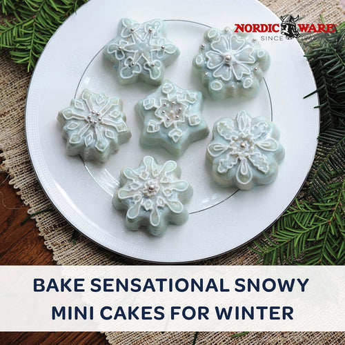 Mini frosted cakes on a plate with greenery and a table linen on a wooden surface with 'bake sensational snowy mini cakes for winter' text beneath it.