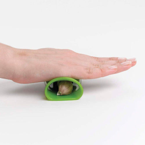 A person using a green rubber garlic peeler on a white background.