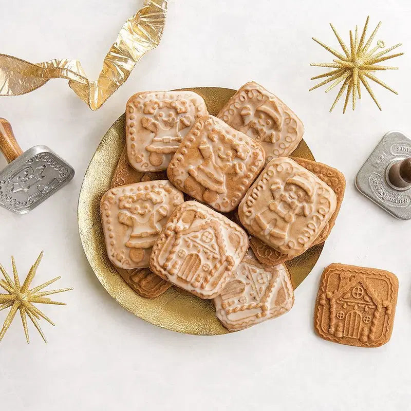 Decorative cookies with embossed designs on a gold plate, surrounded by festive decorations.