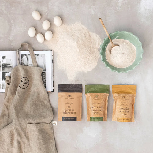 Baking ingredients and mixes with a branded apron on a neutral background