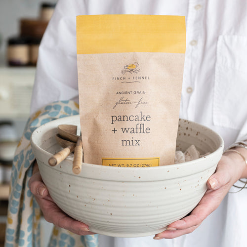 Person holding a bowl with a package of gluten-free pancake and waffle mix.