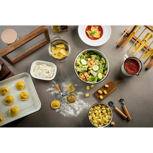 Tabletop scene with various pasta dishes and utensils on a gray surface