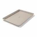 A beige non-stick half-sheet baking pan with micro-textured surface and square rolled edges.