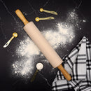 Rolling pin with wooden handle on a black surface with flour and kitchen tools.