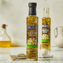 Bottle of Delallo Greek Herb Drizzle Oil on a table with garlic and other ingredients.