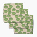 Set of three folded towels with green tomato pattern on a beige background