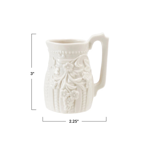 White ceramic pitcher with embossed design and measurements on a white background