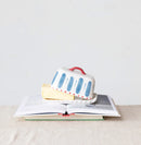 A hand painted butter dish with butter inside on top of books on a neutral background.