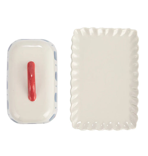 A top down look at a hand-painted butter dish with a scalloped edge dish on a white background.