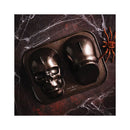 Skull-shaped cake mold on a dark surface with spider decoration