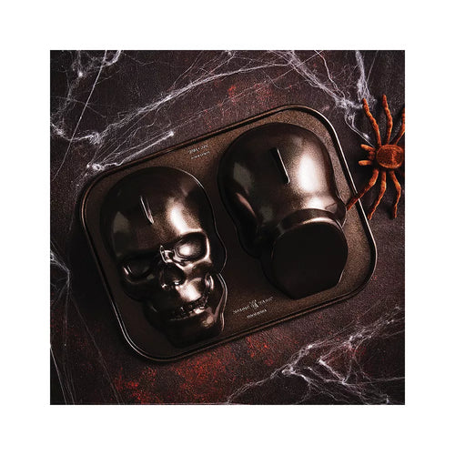 Skull-shaped cake mold on a dark surface with spider decoration
