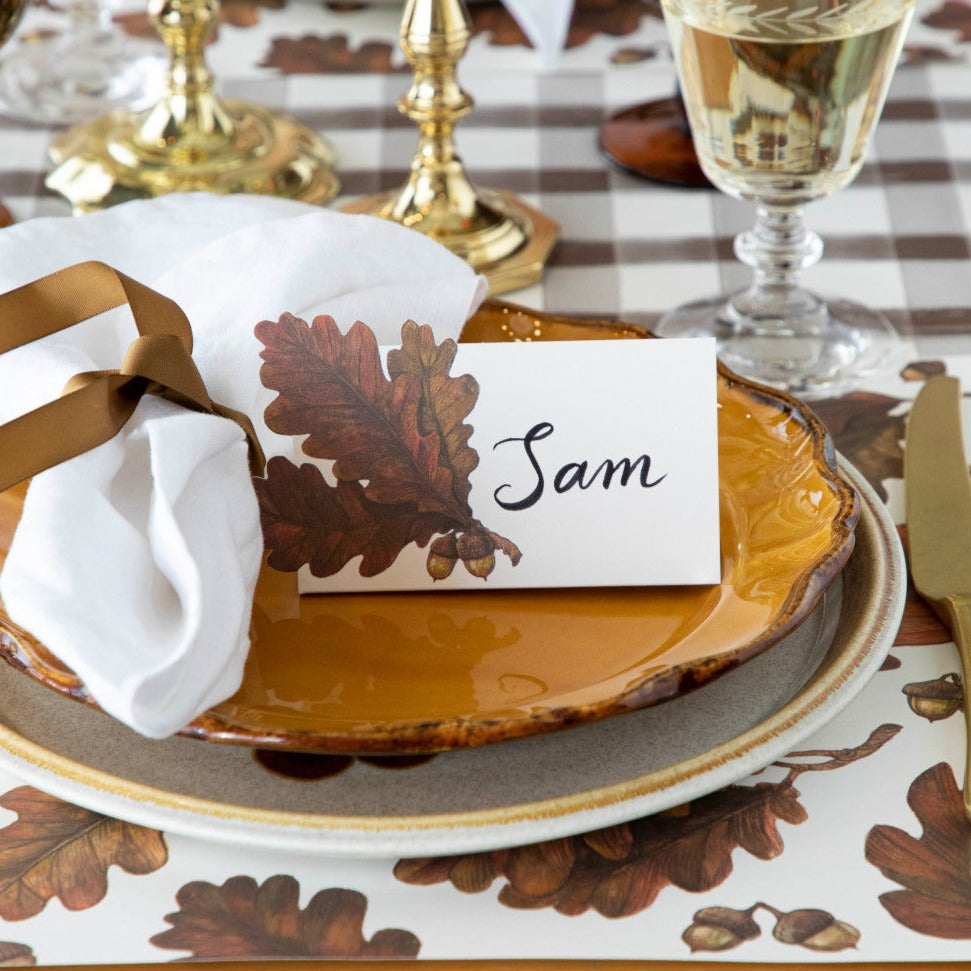 Thanksgiving table setting with place card, leaf design, and gold accents.