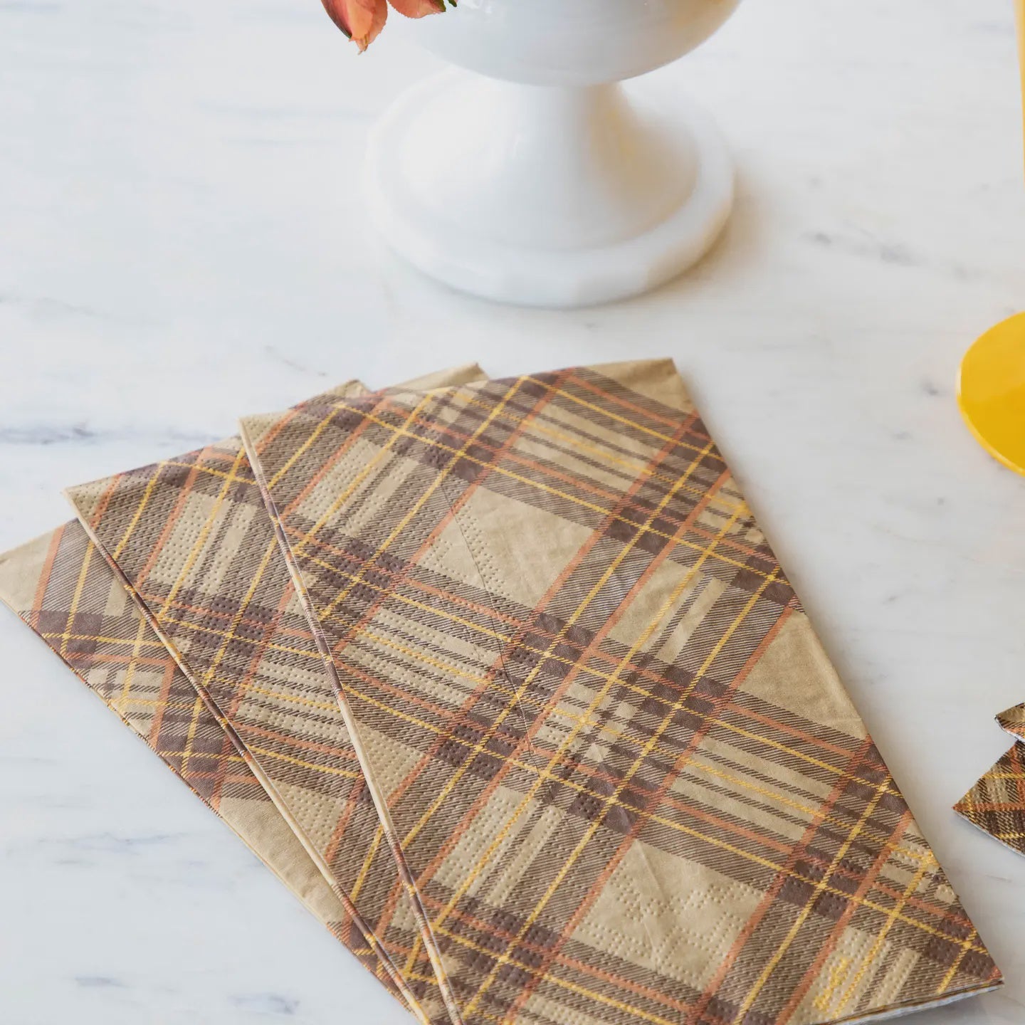 A set of brown plaid napkins on a marble surface.