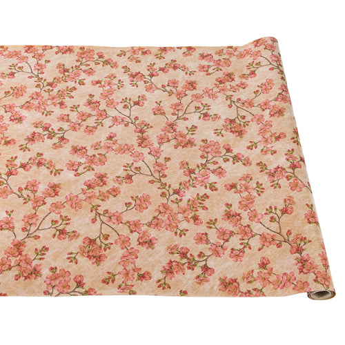 A rolled out paper table runner with a cherry blossom floral pattern on a beige background.