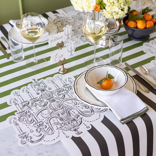 Elegant table setting with striped tablecloth, chandelier drawn placemats, and place cards.