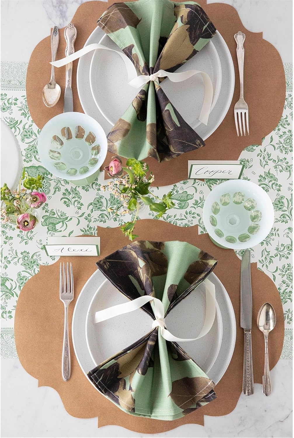 Two place settings at a table featuring fabric napkins and French frame placemats.