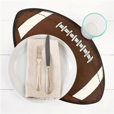A football placemat beneath a glass, plate, and napkin with fork and knife on a white surface.