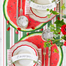 Two place settings featuring name cards, silver flatware, a paper watermelon placemat, and striped table runner.