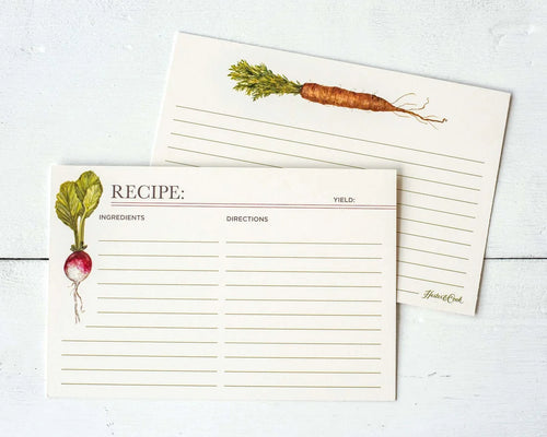 Two cream recipe cards with botanical vegetable illustrations, one showing a radish and the other a carrot, laid flat on a white wood background.