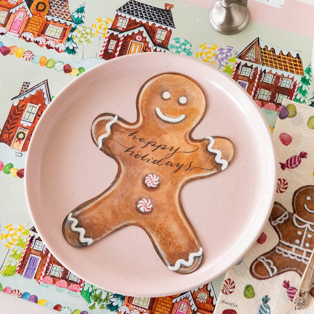 Gingerbread man cookie with 'happy holidays' on a pink plate, colorful gingerbread-themed background