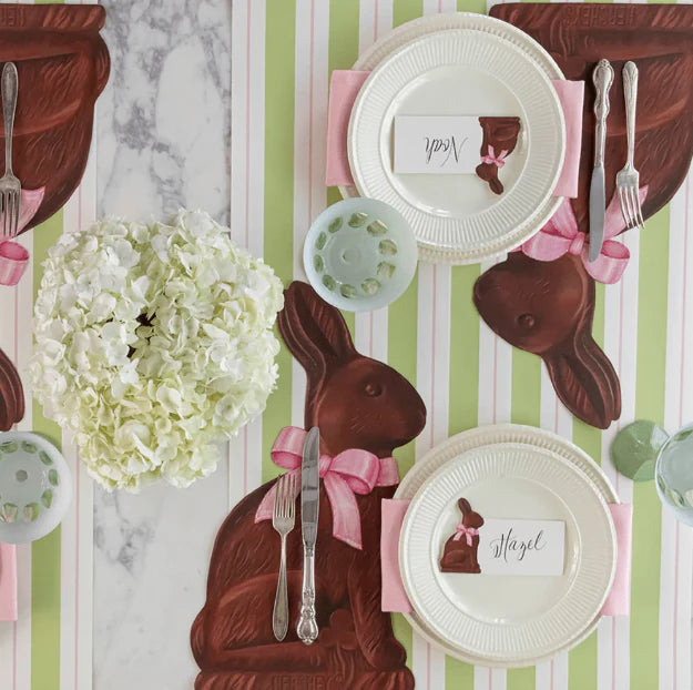 Easter-themed table setting with chocolate bunny-shaped placemats and decorative elements.
