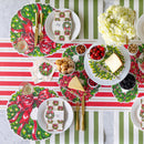 Christmas-themed table setting with decorative plates and striped tablecloth.