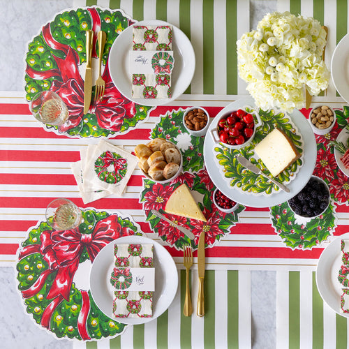 Christmas-themed table setting with decorative plates and striped tablecloth.