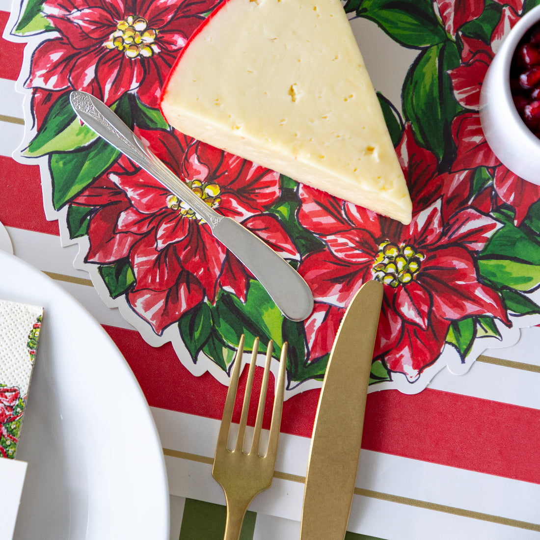 Cheese with cutlery on a Christmas-themed placemat with poinsettias