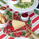 Cheese platter with bread and pomegranate seeds on a Christmas-themed tablecloth.
