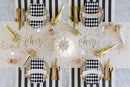 A celebratory place setting with a "cheers" table runner, black and white decor, napkins, and cake.