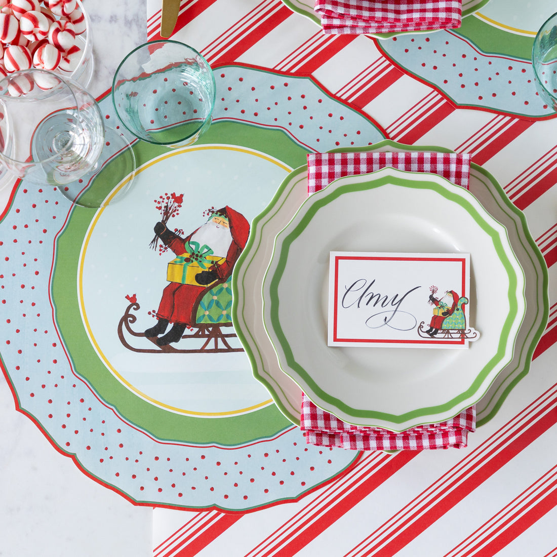 Christmas-themed table setting with decorative plates and a striped tablecloth.