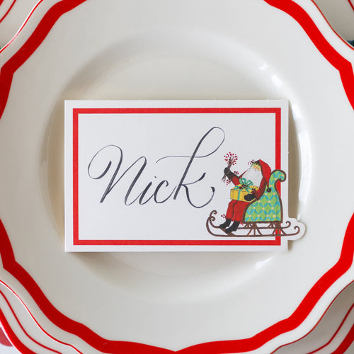 Name card with Santa Claus design on a white plate with red rim
