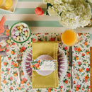 Dining table setting with floral placemat, yellow napkin, and colorful candy.