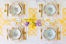 Elegant table setting with floral plates, gold cutlery, and yellow plaid tablecloth.