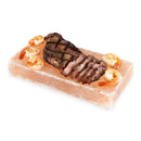 A pink Himalayan salt block with steak and shrimp on it.