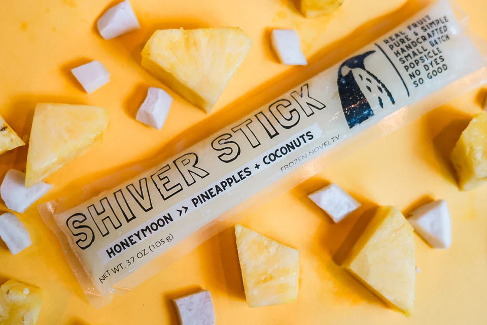 Shiver Stick popsicle with pineapple and coconut pieces on a yellow background