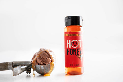 Bottle of hot honey with a scoop of ice cream on a white background