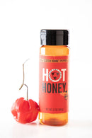 Bottle of hot honey with a Scotch bonnet pepper on a white background