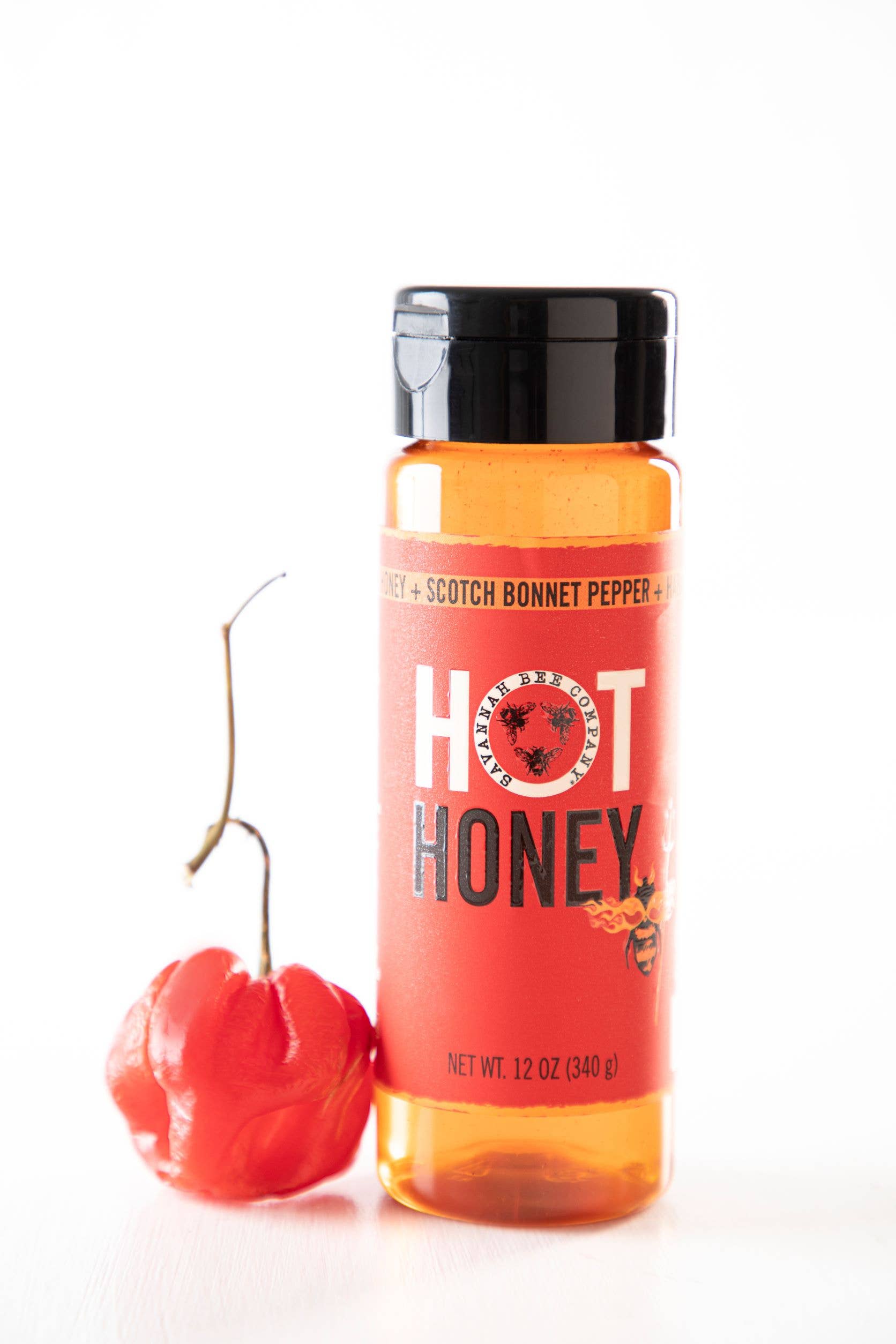 Bottle of hot honey with a Scotch bonnet pepper on a white background