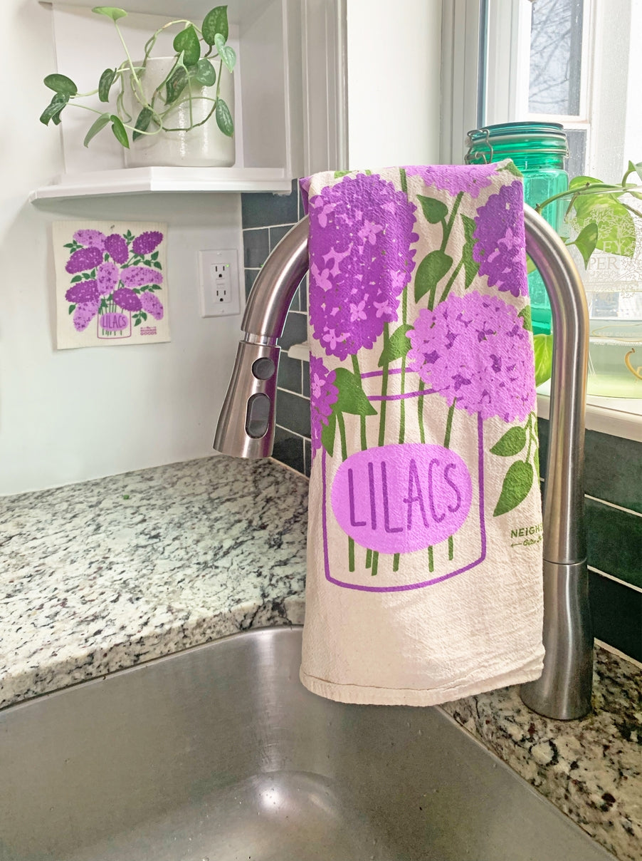 Kitchen towel with purple lilac design hanging over a sink