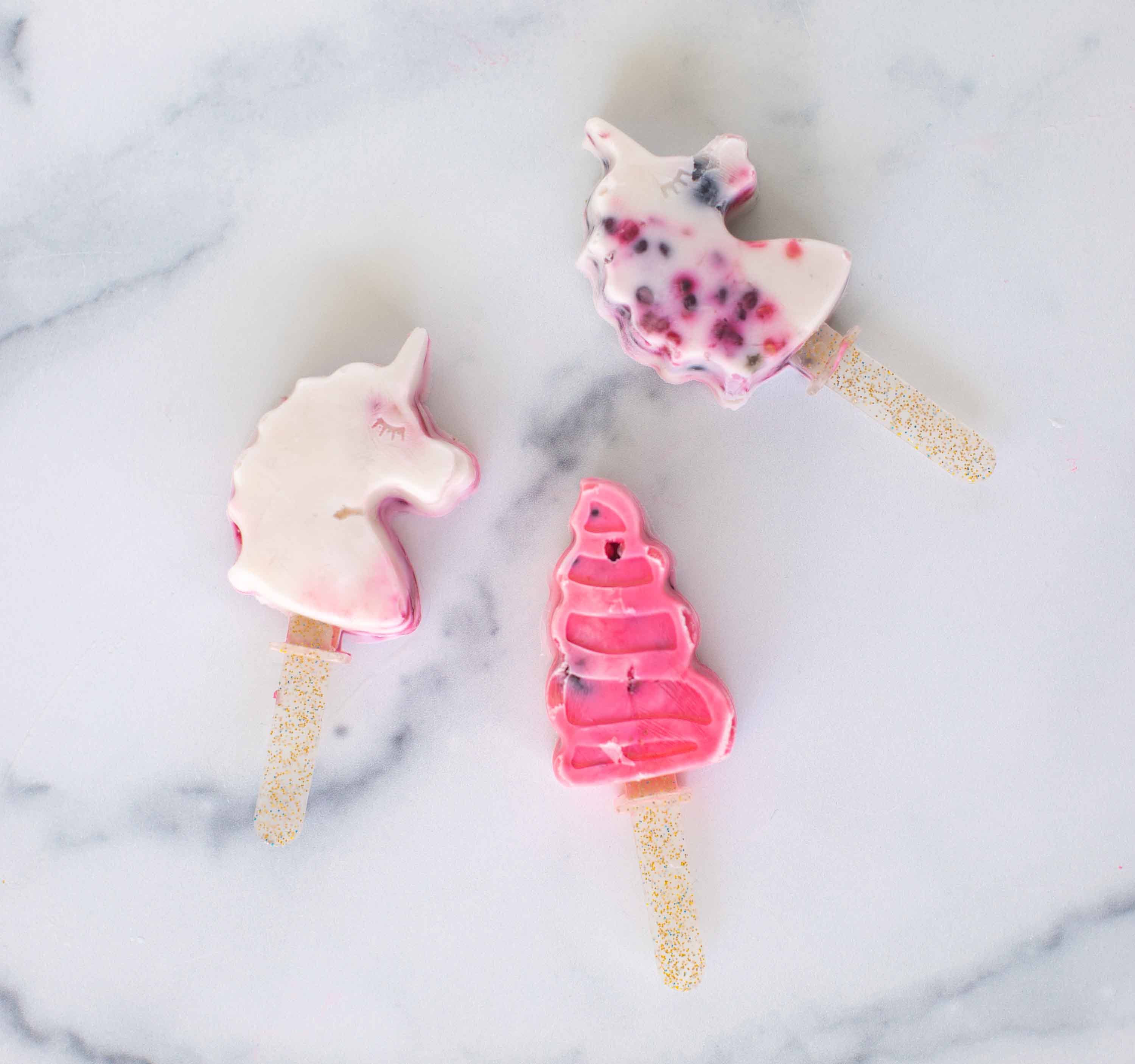 Ice pops in unicorn shapes on a marble background.