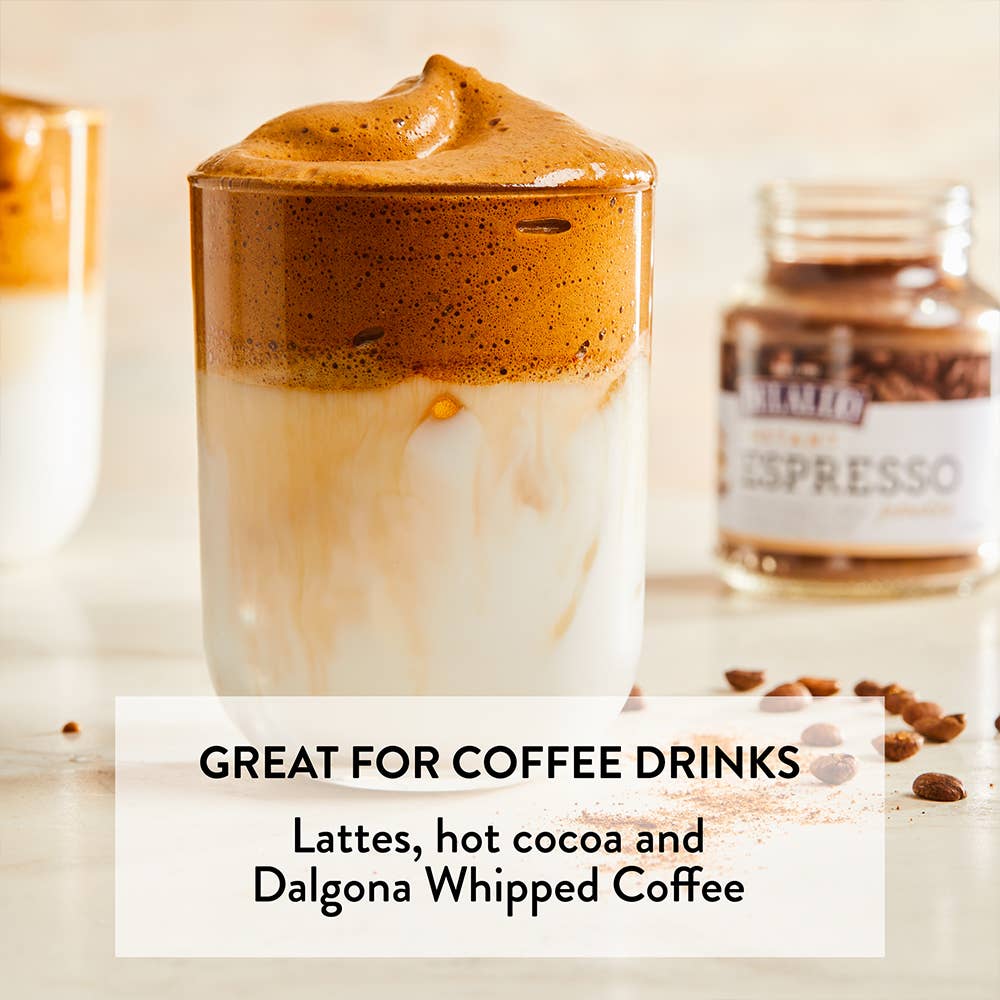 Glass of whipped coffee with a jar labeled 'Espresso' on a wooden surface.