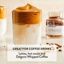 Glass of whipped coffee with a jar labeled 'Espresso' on a wooden surface.
