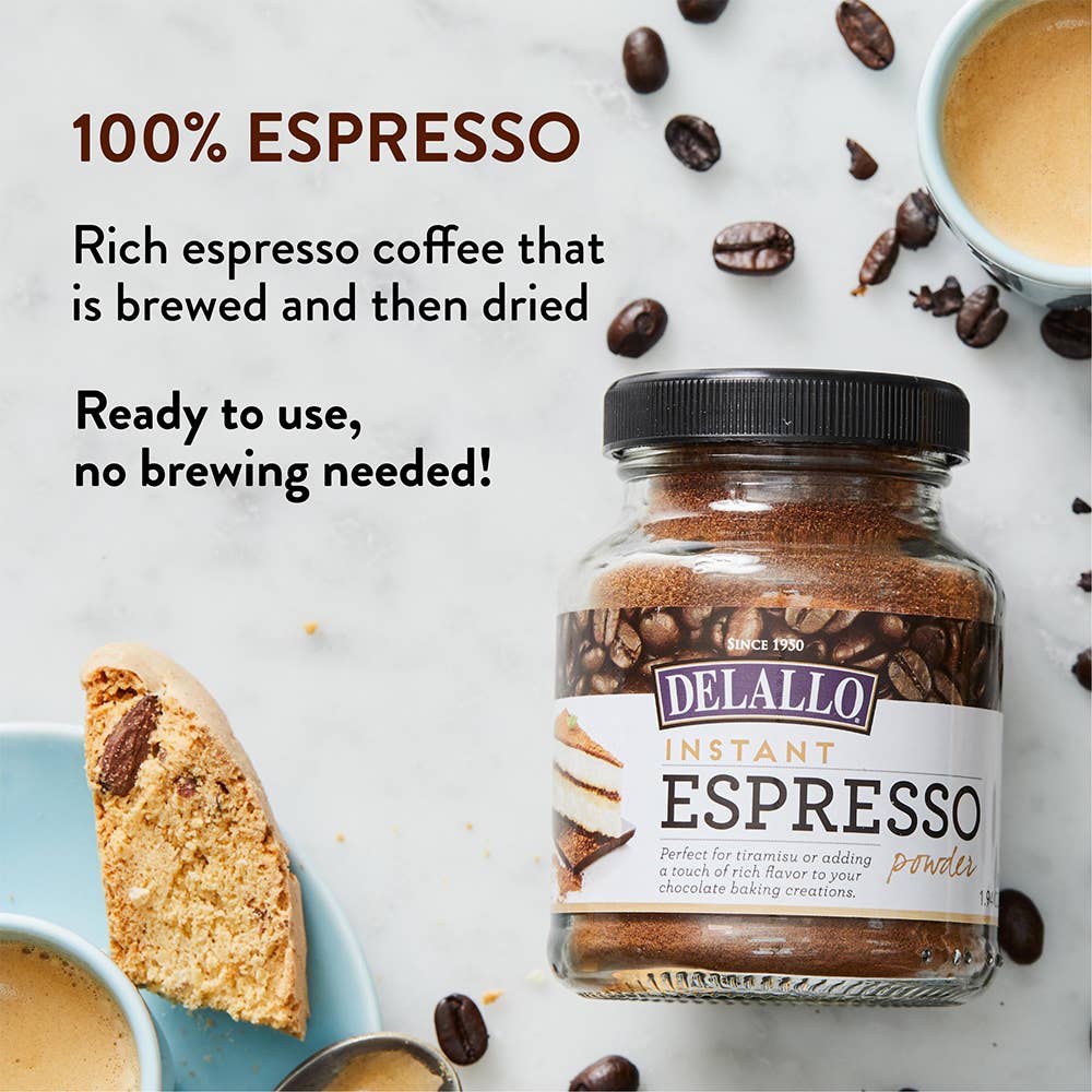 Jar of Delallo Instant Espresso powder with coffee beans and a biscotti on a marble surface.