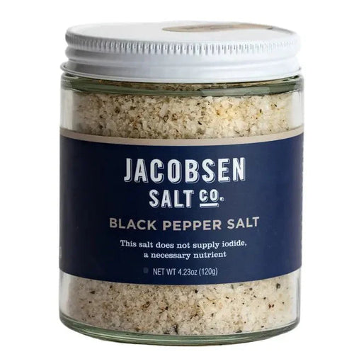 A clear glass jar with a label reading 'Jacobsen Salt Co. Black Pepper Salt', indicating the product is infused sea salt with black pepper.