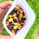Hand holding a container of tea mix  against a green outdoor background