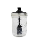 Clear glass jar with black lid and basting brush on a white background