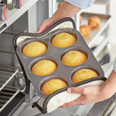 A person holding a jumbo muffin pan with muffins inside.
