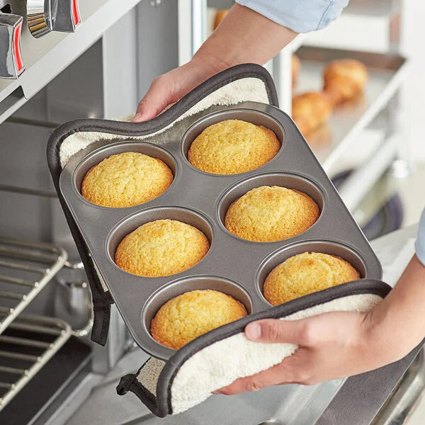 A person holding a jumbo muffin pan with muffins inside.